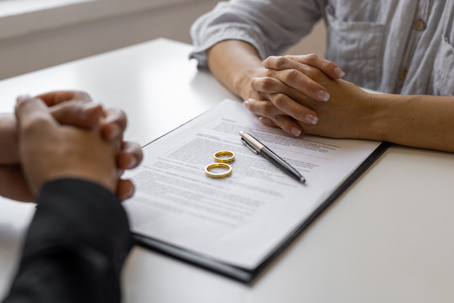 Couple sitting across from each other with wedding rings and documents in the middle