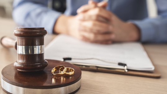 Wedding rings on top of a gavel with documents behind